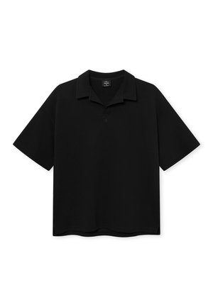 Polo shirt nera a maniche corte con colletto a pieghe, vestibilità ampia e logo discreto sul petto, presentata su uno sfondo bianco.