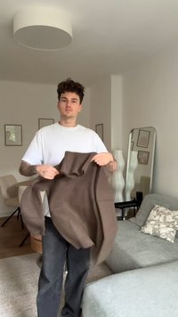 Pruun ribadega kootud sviiter, millel on kõrge krae ja lõdvestatud lõige. Mudel kannab valget T-särki ja musti pükse, kerge interjööri taustal.