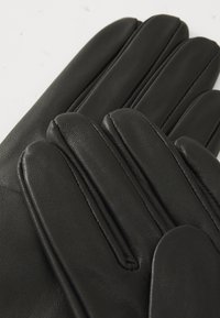 Luvas de pele preta com uma textura suave, cinco dedos e costuras visíveis. O design apresenta uma forma clássica e detalhes subtis.