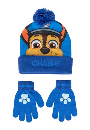 Bonnet tricoté bleu avec un visage de personnage et un pompon sur le dessus, associé à des gants bleus assortis présentant des motifs de empreintes de pattes sur les paumes.