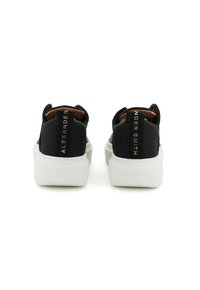 Sneakers neri con suole bianche, caratterizzati da una texture liscia e linguette posteriori. La scritta dorata sul retro recita "ALEXANDER SMITH."