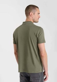 Olijfgroen polo-shirt met korte mouwen, een kraag en subtiele stiksels. De stof lijkt glad met een getailleerde pasvorm aan de achterkant.