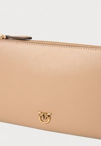 Portafoglio in pelle beige con finitura testurizzata, chiusura a zip e accentuazione del logo in tonalità oro con due uccelli.
