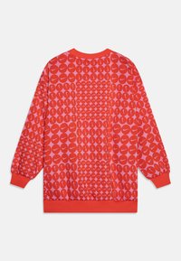 Sweatshirt rouge à col rond avec un motif couvrant de logos Nike se chevauchant de différentes tailles, des poignets et un col côtelés.