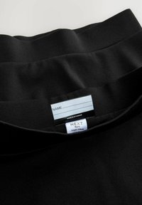 Zwarte kledingstukken met een gladde textuur; bevat een waslabel en maatlabel waarop 'NEXT 6 jaar' en 'lengte 116 cm' staat.