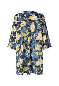 Bloemmotief tuniek in blauw, geel en zwart op een crèmekleurige achtergrond. Kenmerkt zich door een losse pasvorm, driekwartmouwen en een knoopsluiting bij de kraag.