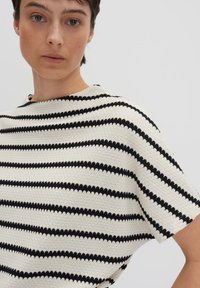 Maglione a righe in crema e nero, caratterizzato da un pattern testurizzato, vestibilità rilassata e maniche corte con scollatura a girocollo.