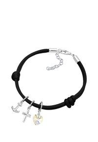 Svart snoddarmband med silverfärgade charm: ankare, kors och iriserande hjärta. Har justerbar lås och texturerade knutar.
