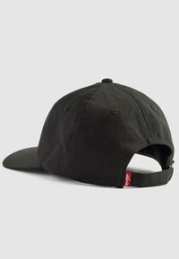 Casquette de baseball en coton noir avec une visière courbée, une sangle ajustable à l'arrière et une étiquette rouge Levi's sur le côté. Surface en tissu texturé.