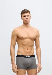 Szürke pamut boxeralsó fekete derékrésszel, amelyen a „BOSS” logó látható. Az anyag puhanak, testhez simulónak és rugalmasnak tűnik.