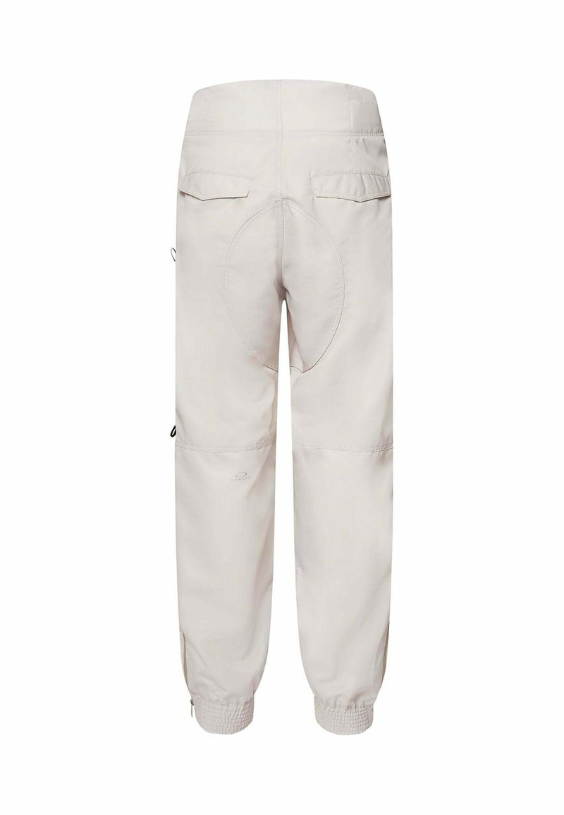 Helle beigefarbene Cargo-Hosen mit elastischen Bündchen, zwei Gesäßtaschen und einem ovalen Designdetail im Bereich des Gesäßes. Hergestellt aus einem glatten, strapazierfähigen Stoff.