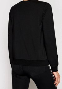 Zwarte sweatshirt met lange mouwen, voorzien van een ronde hals en ribgebreide manchetten en onderkant. Het materiaal lijkt zacht met een gladde textuur.