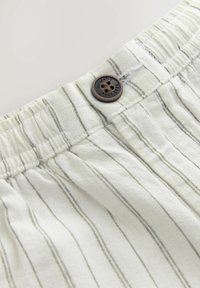 Light cream fabric shorts featuring vertical grey stripes, elastic waistband, and a dark brown button detail at the top.