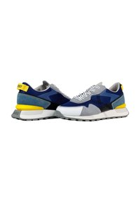 Zapatillas deportivas que combinan malla azul, ante gris y materiales sintéticos blancos; acentos amarillos en el talón y suela de goma gris.