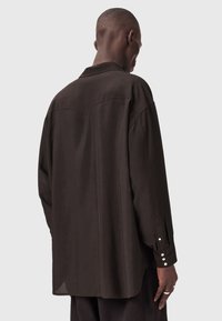 Καφέ πουκάμισο με κουμπιά, άνετη εφαρμογή, με ομαλή υφή, αιχμηρό γιακά και μανσέτες με κουμπιά. Η πίσω πλευρά έχει λεπτομέρεια yoke.