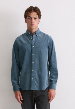 Blauwe button-down overhemden gemaakt van corduroy-stof met een gestructureerd oppervlak, voorzien van een puntkraag en witte knopen. Gekocht met donkere jeans.