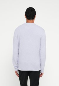 Pulover tricotat mov deschis cu mâneci lungi și guler rotund. Material moale, texturat, cu croială lejeră și tiv drept. Fără accente vizibile.