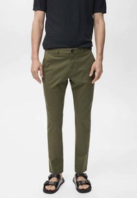 Olive green trousers with a slim fit, made of cotton blend fabric, featuring a front button closure and side pockets. Worn with black sandals.