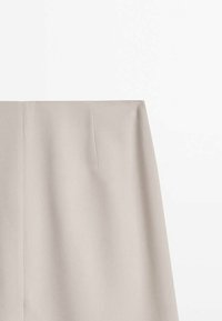 Beige tailored skirt with a smooth texture, featuring two front pleats and a straight cut, designed to sit at the waist.