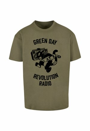 T-shirt in cotone verde oliva con una grafica nera di un gatto con un boombox, testo "GREEN DAY REVOLUTION RADIO" sopra e sotto.