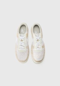 Nike Air kedas ar krēmkrāsas un baltu adītu augšdaļu, baltām auklām un mīkstinātu zoli. Izstrādātas ar smalku teksturētu rakstu.