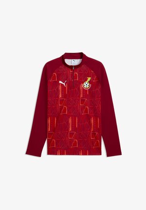 Langärmeliges, kastanienbraunes Sportoberteil mit geometrischen Mustern, Puma-Logo auf der rechten Brust und Emblem des Ghana Football Association auf der linken Brust.