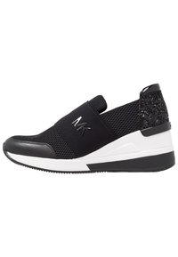 Sneaker in mesh nera con fascia elastica nera, dettaglio lucido sul tallone e suola bianca. Presenta un retro testurizzato e un logo sulla fascia.