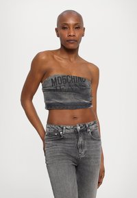Hallhalli denimga tasuta topp musta "MOSCHINO JEANS" logoga, koos hallide kõrge vöökohaga teksadega, millel on tekstuurne välimus.