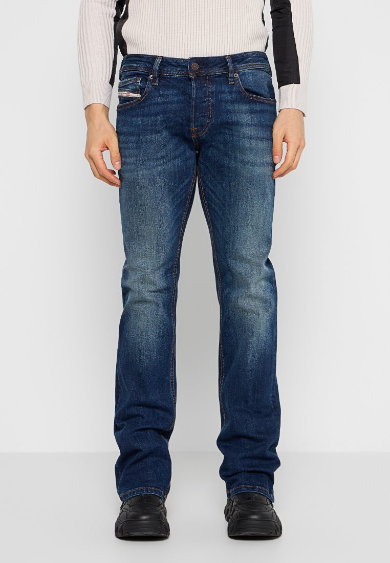 Dunkelblaue Jeans aus Denim mit geradem Bein. Zu den Merkmalen gehören dezente Verwaschungen, fünf Taschen und kontrastierende Nähte. Silberne Hardware-Details.