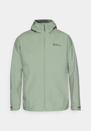 Giacca impermeabile verde chiaro con cappuccio, zip frontale e logo sulla parte superiore sinistra. Presenta polsini regolabili e una texture liscia.