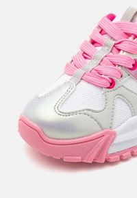 Scarpa sportiva con tomaia in mesh bianco e dettagli argento, lacci rosa e suola in gomma rosa testurizzata. Punta arrotondata e design ammortizzato.