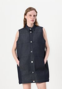 Kangaskankaan hihaton mekko tummansinisena, jossa on klassinen kaulus, edessä napit ja kaksi sivutaskua. Hieman teksturoitu rakenne, jossa on jämäkät paneelit.