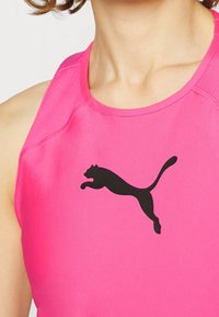 Rosa ärmlös sporttop i slät tyg med en stor svart Puma-logga. Urringningen är rund med synliga sömdetaljer.