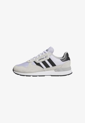 Adidas sneakers in light gray suede and mesh with black stripes, white sole, lace-up design, and logo accents on tongue and heel.