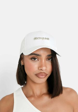 Cappellino da baseball bianco con visiera curva e logo metallico "SIXTHUNE" sul davanti. Presenta dettagli di cucitura e una texture di tessuto liscia.