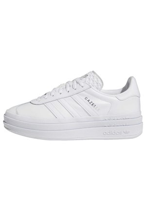 Baskets blanches Adidas Gazelle avec semelle épaisse, trois bandes sur le côté, lacets et logos embossés sur la languette et la semelle intermédiaire.