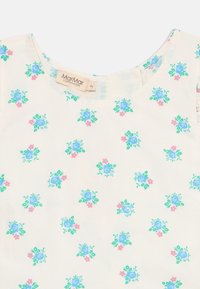 Ärmelloses Blumenkleid aus einem hellen cremefarbenen Stoff, mit verstreuten blau- und rosa Blütenmustern sowie einem runden Ausschnitt. Etikett sichtbar.