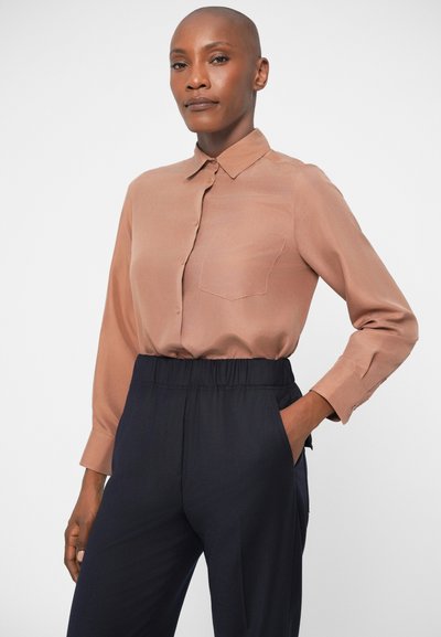 Long-sleeve, collared shirt in soft brown fabric with a chest pocket, paired with dark navy elastic waistband pants, featuring side pockets.