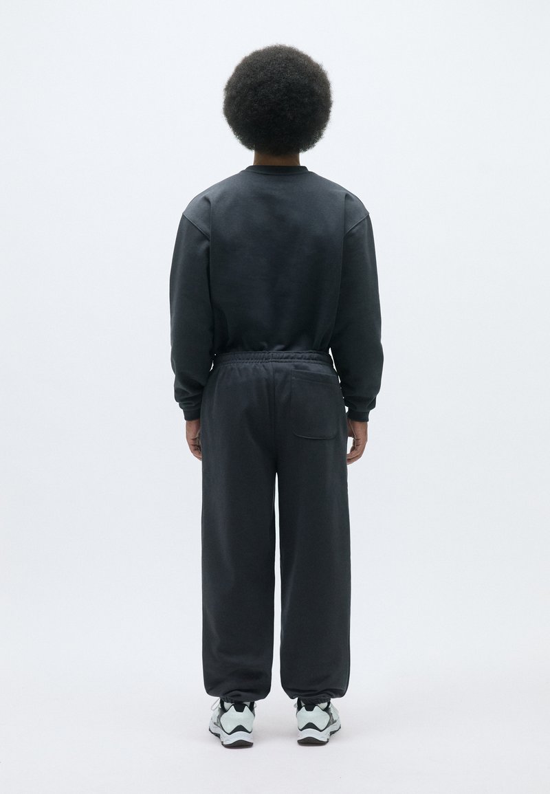 Mørkegrå sweatshirt og bukser, begge lavet af blødt stof. Løs pasform, med rund hals og elastisk talje. Har en baglomme.