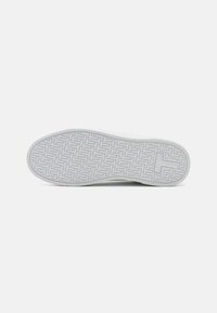 Suela de zapatilla blanca con un patrón texturizado de espiga y un borde redondeado, con un mínimo de marcas y una superficie lisa.