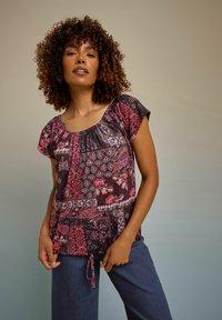 Blusa multicolore con scollatura arricciata, maniche corte, motivi floreali e geometrici in patchwork e un dettaglio con coulisse all'orlo.