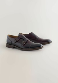 Donkerbruine leren schoenen met een strak ontwerp. Voorzien van dubbele gespen en een gladde textuur, ronde neus en contrasterende stikdetails.