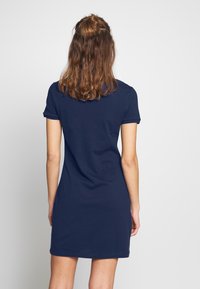 Abito in cotone blu navy con maniche corte e vestibilità rilassata. Texture liscia, lunghezza al ginocchio, con un design semplice e non decorato.