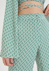 Grön och vit blommönstrad outfit med en kort topp med justerbara band och vida byxor. Slät, lätt tygtextur.