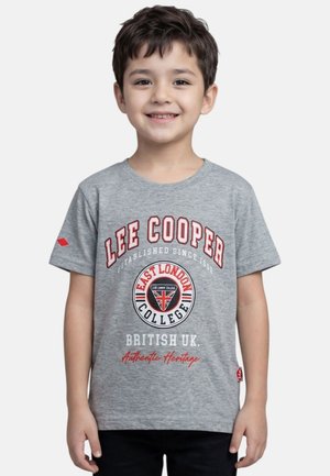Jeune garçon souriant aux cheveux foncés portant un t-shirt gris Lee Cooper avec un logo et un texte rouge et blanc du East London College.