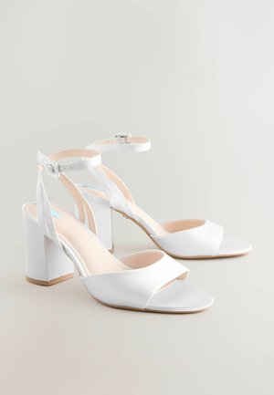 Weiße High-Heelsandalen mit satinierter Oberfläche, offener Zehenpartie, gekreuzten Riemen, verstellbarem Knöchelriemen und klobigem, quadratischem Absatz.