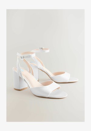 Weiße High-Heelsandalen mit satinierter Oberfläche, offener Zehenpartie, gekreuzten Riemen, verstellbarem Knöchelriemen und klobigem, quadratischem Absatz.