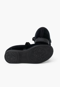 Zapatos mary jane de terciopelo negro con correa ajustable, punta redonda y suela de goma texturizada que presenta patrones de flores y corazones.