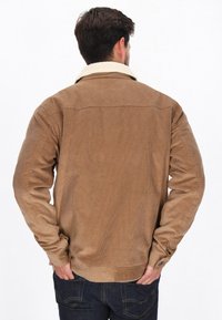 Braune Cordjacke mit einem cremefarbenen Kunstpelzkragen, geknöpften Manschetten und einem strukturierten Stoff, von hinten gezeigt.