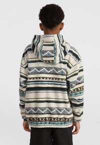 Fleece hoodie met een witte basis voorzien van blauwe en groene geometrische patronen, gestreepte accenten en een capuchon met koordjes. Zachte textuur.